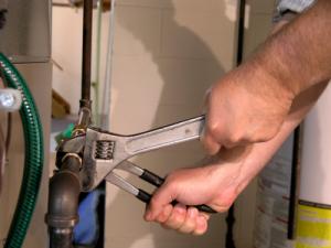 A plumber in Downey tightens a hot water line connection